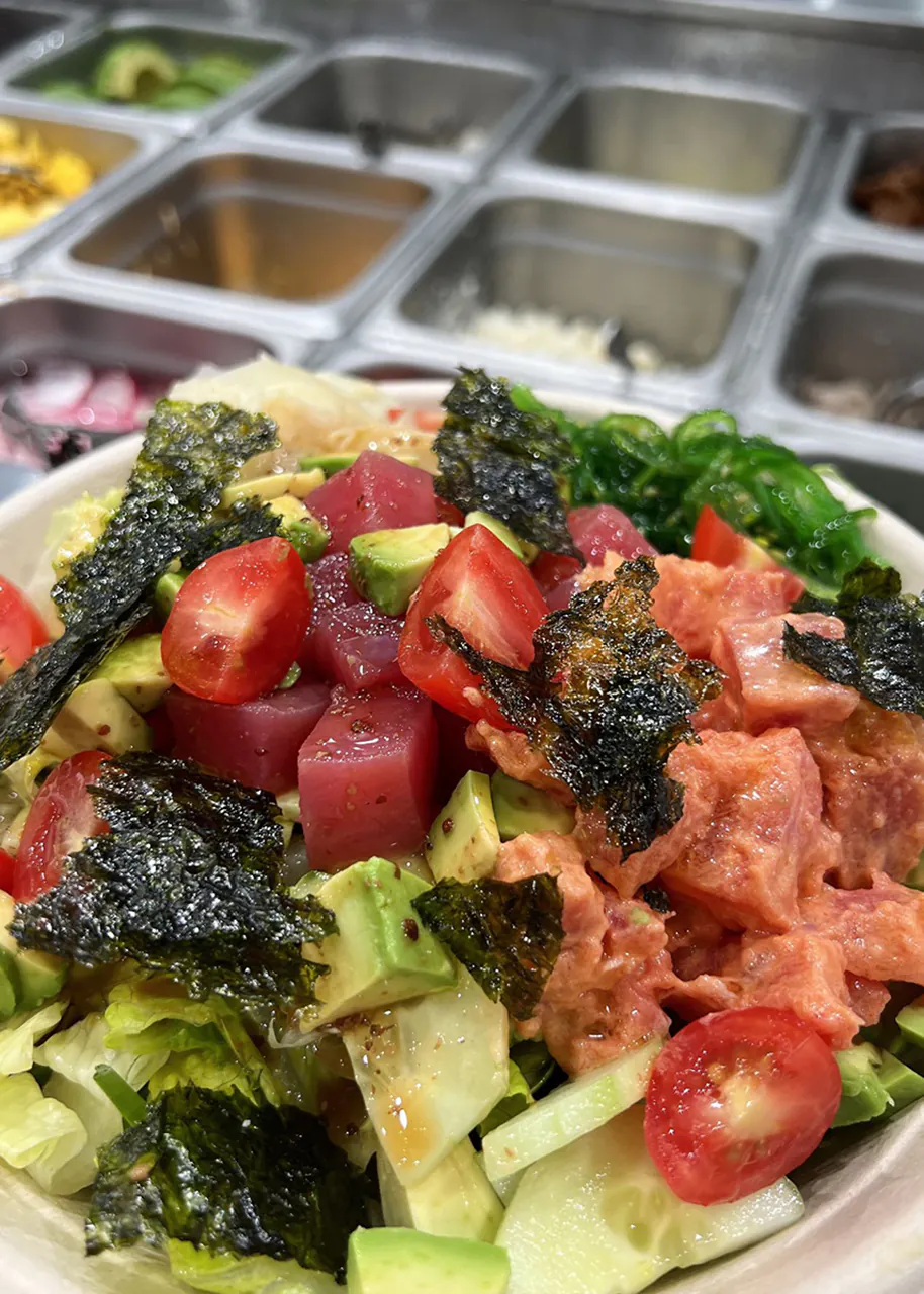 Fresh poke bowl with tuna, salmon, avocado, tomatoes, seaweed, and salad greens at Natural Kitchen Wilton, a Fast Casual Restaurant in Wilton